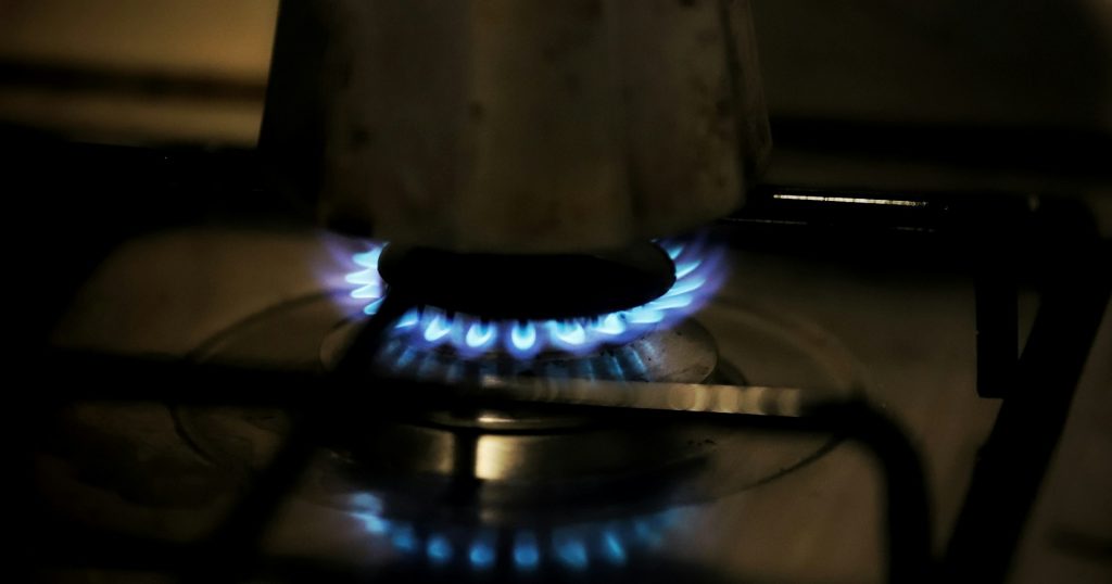 A gas stove with blue flames in a dark room
